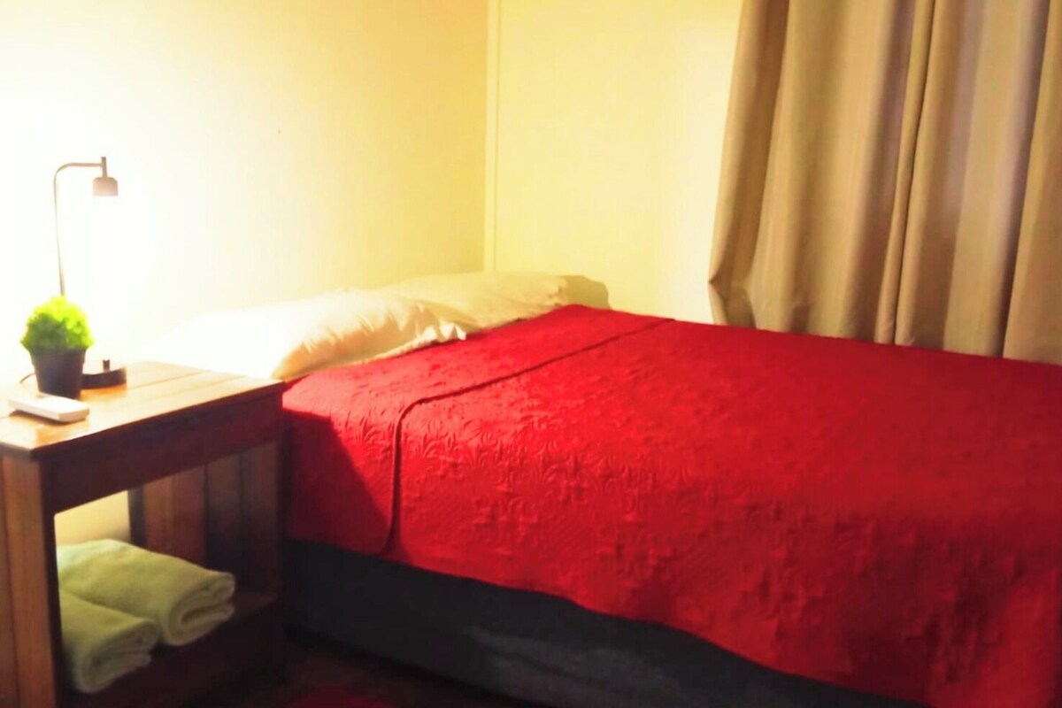 Une chambre avec un lit, une table de chevet, une lampe et une plante en pot.