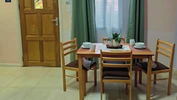 A dining area with a wooden table and chairs, a potted plant, and a door with a sign.
