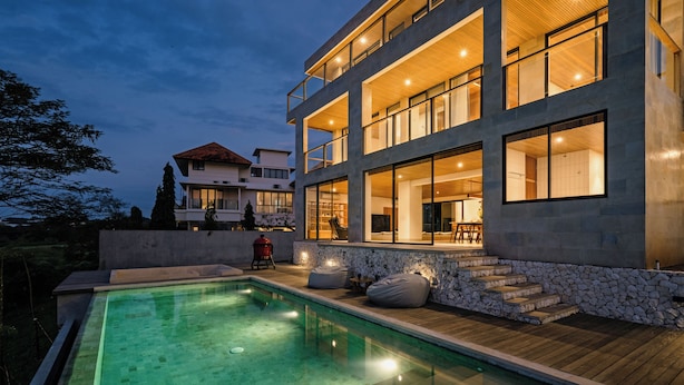 Un edificio moderno de varios pisos con piscina, escalones de piedra y terraza de madera.
