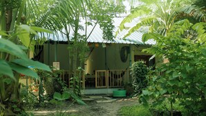 Um edifício rústico com telhado de metal corrugado, rodeado por vegetação tropical densa.