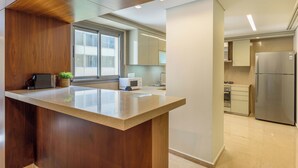 A modern kitchen with a wooden accent wall, a built-in island, and stainless steel appliances. - Solidere Lavish Apartments in Downtown Beirut (Beirut)