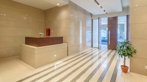 A modern lobby with a reception desk, a potted plant, and a striped floor. - Solidere Lavish Apartments in Downtown Beirut (Beirut)