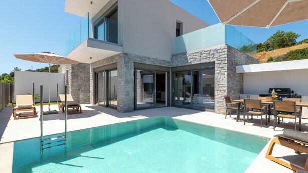 A modern house with a swimming pool, outdoor seating, and a barbecue area.