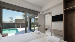 A modern hotel room with a large bed, a TV mounted on the wall, and a sliding glass door leading to a pool area.