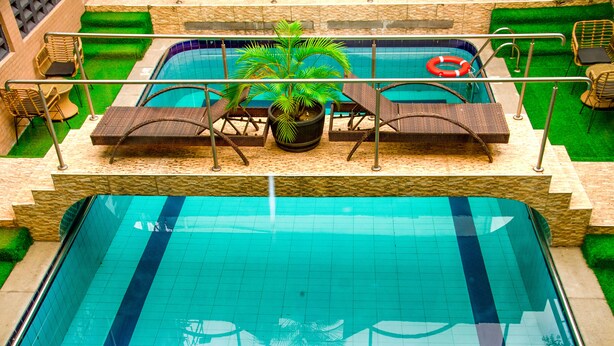 A swimming pool with a lifebuoy, lounge chairs, and a potted plant. - Kdovehotels&suites (Lagos)