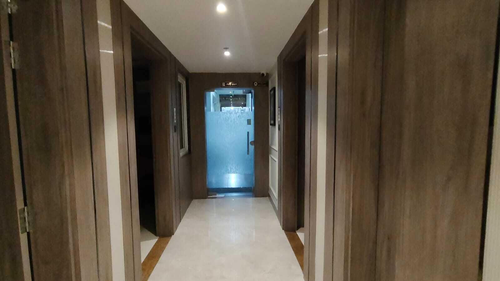 A hallway with wooden doors and a tiled floor leading to a room with a window.