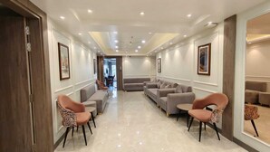 A modern lounge area with sofas and chairs arranged for seating, a polished floor, and framed artwork on the walls. - Park View (Varanasi)