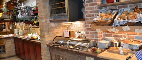 A breakfast bar with a coffee machine, a fruit bowl, and a variety of pastries.