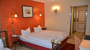 A hotel room with a double bed, two bedside tables, a red accent wall, and a framed picture on the wall. - Gasthaus Gästekiste (Augsburg)