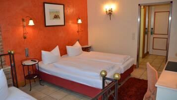 Habitación de hotel con una cama doble, dos mesitas de noche, una pared de acento roja y un cuadro enmarcado en la pared.