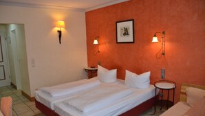 Una cama doble con ropa de cama blanca, dos mesitas de noche y dos lámparas de pared.