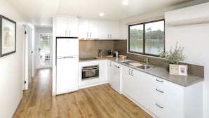Een moderne keuken met witte kasten, een roestvrijstalen spoelbak en een groot raam met uitzicht op het water.
