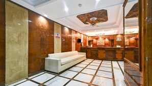 A lobby with a reception desk, a white sofa, and a patterned ceiling. - Hotel Geet Deluxe (New Delhi)