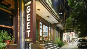 A hotel named "Hotel Geet Deluxe" with a staircase leading to the entrance, surrounded by potted plants and other buildings. - Hotel Geet Deluxe (New Delhi)