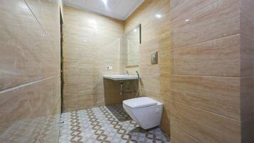 A bathroom with a toilet, sink, and shower area, featuring patterned floor tiles and beige walls.