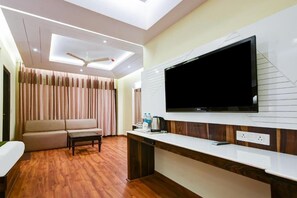 Una habitación de hotel moderna con un televisor de pantalla plana en la pared, un sofá, una mesa de centro y piso de madera.