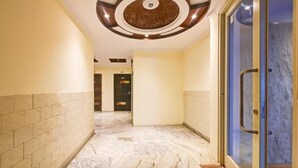 A corridor with marble flooring, a glass door on the right, and a circular ceiling design. - Hotel Geet Deluxe (New Delhi)