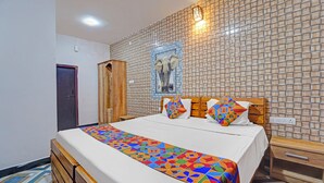 Habitación de hotel con una cama grande, un armario de madera, pared con azulejos y un cuadro enmarcado de un elefante.