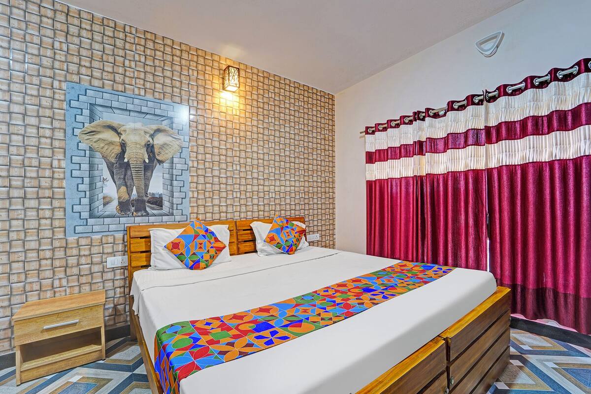 A bedroom with a brick-patterned wall, a bed with a colorful geometric bedspread, and a red curtain.