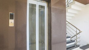 A modern building entrance with a glass door, a metal staircase, and a wall-mounted intercom. - Fabhotel Empire (Indore)