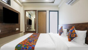 A hotel room with a bed, a TV mounted on the wall, and a wardrobe with a mirror. - Fabhotel Empire (Indore)