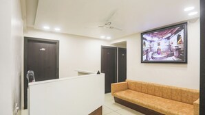 A reception area with a reception desk, a sofa, and a ceiling fan. - Fabhotel Empire (Indore)