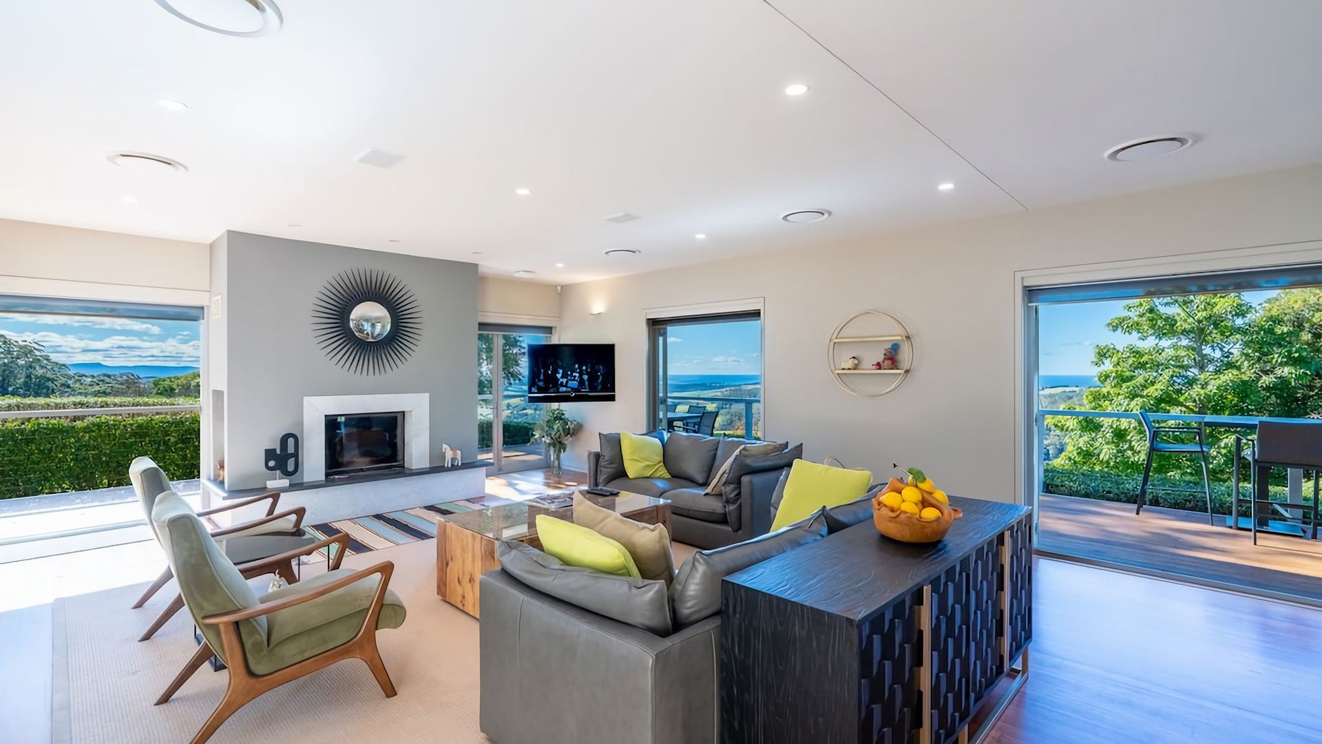 A modern living room with a fireplace, comfortable seating, and a large window offering a scenic view.