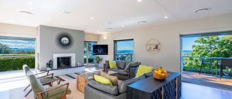 A modern living room with a fireplace, comfortable seating, and a large window offering a scenic view.