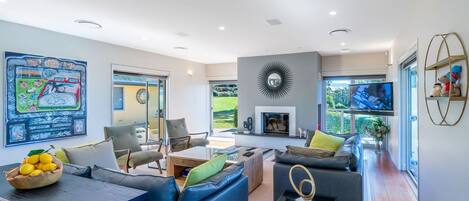 Una sala de estar moderna con chimenea, asientos cómodos y un amplio ventanal.
