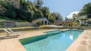 A swimming pool with a clear blue water surface, surrounded by a stone deck.