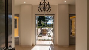 A hotel entrance with a chandelier, a patio with a table and chairs, and a view of the outdoors.