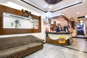A hotel reception area with a sofa, a reception desk, and a staircase.