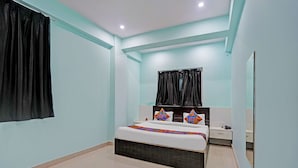 A bedroom with a bed, a nightstand, a mirror, and a window with curtains. - Fabhotel Maa Tara (Danapur)