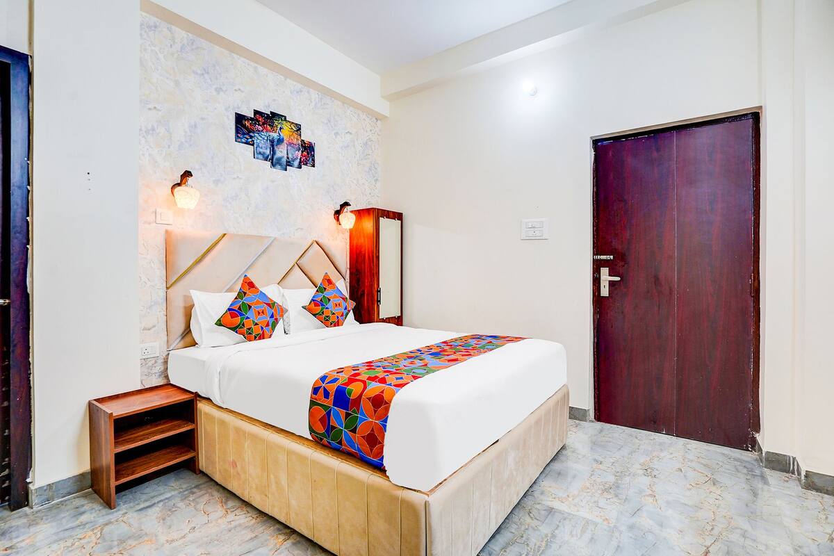 A neatly arranged bedroom with a bed, bedside tables, a wall-mounted artwork, and a door.