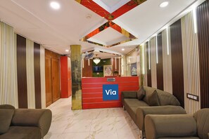 A reception area with a red reception desk, a chandelier, and a television on the wall. - Via AK Continental (New Delhi)