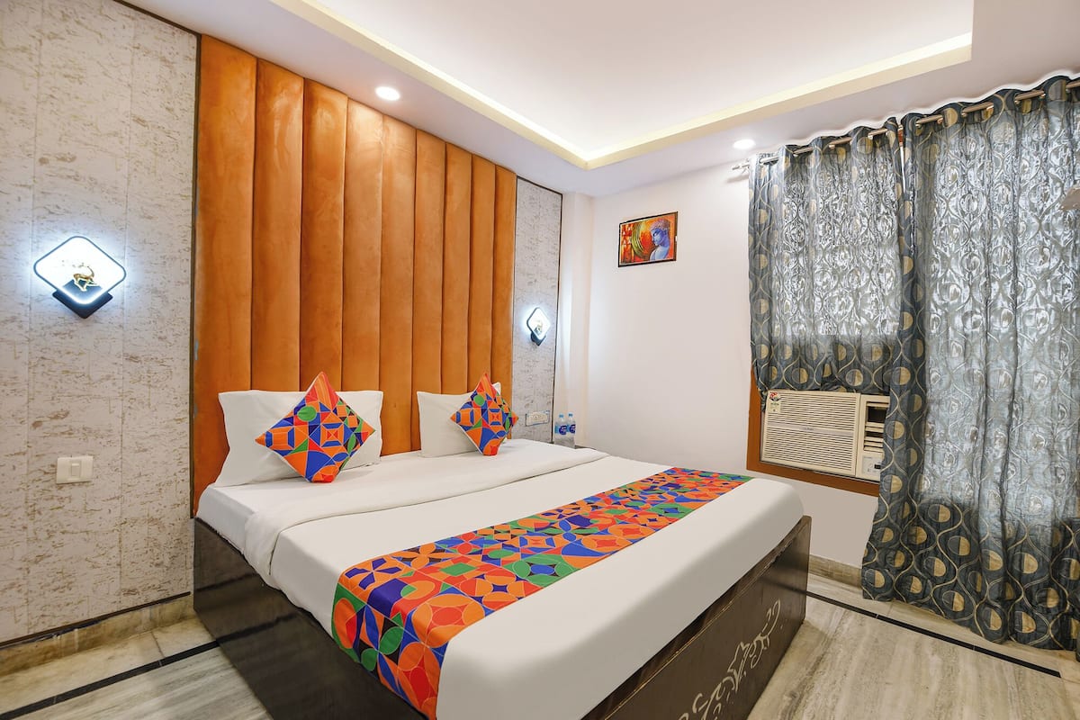 Una habitación de hotel moderna con una cama grande, cabecera de madera y una colcha estampada.