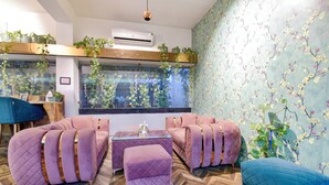 A modern lounge area with a large window, a water feature, and a floral wallpaper design. - Fabhotel Shikha (Jaipur)