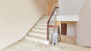 A staircase with a wooden handrail and a fire exit sign on the wall. - Fabhotel Shikha (Jaipur)