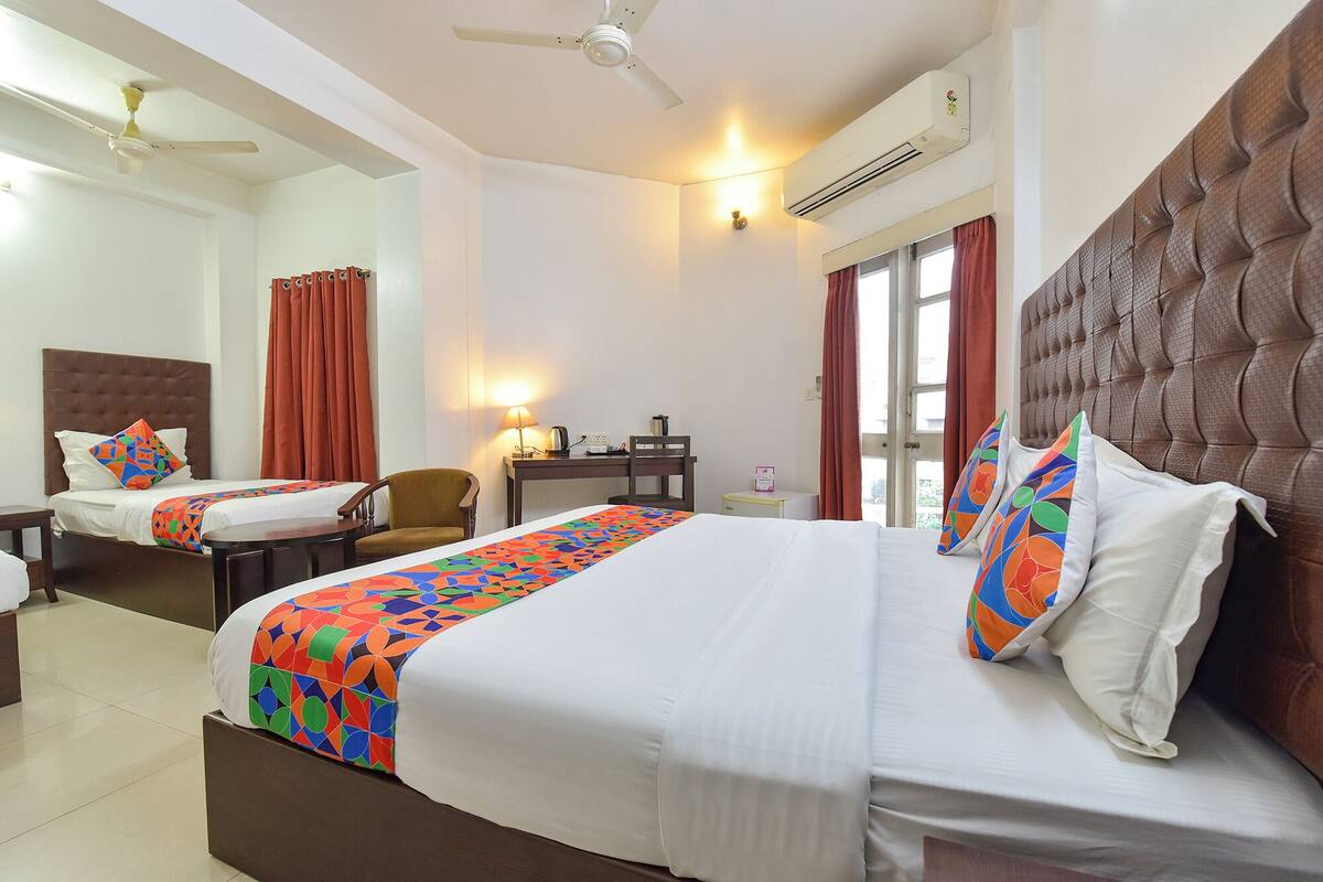 Une chambre d’hôtel avec deux lits, un bureau, une chaise, une lampe et un appareil de climatisation.