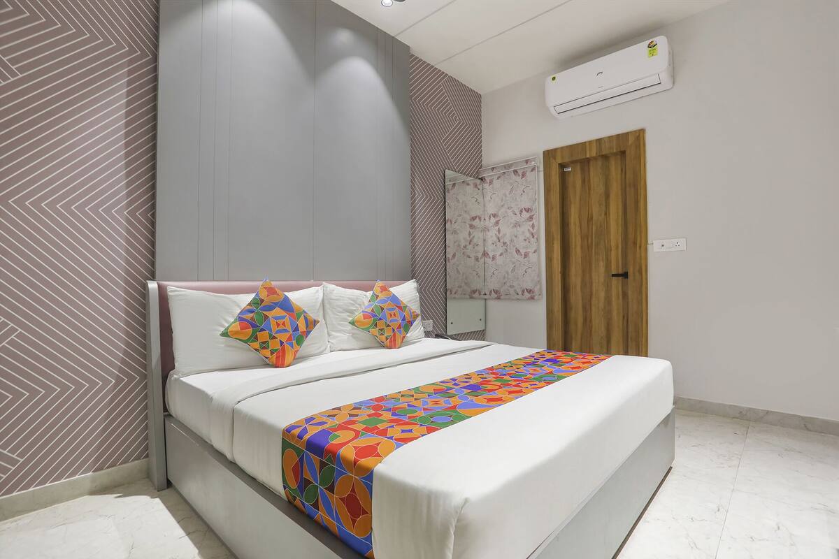 A modern bedroom with a bed, pillows, and a colorful blanket.