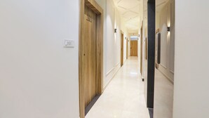 Ein moderner Hotelkorridor mit Holztüren, einem hellen Boden und eingelassener Deckenbeleuchtung.