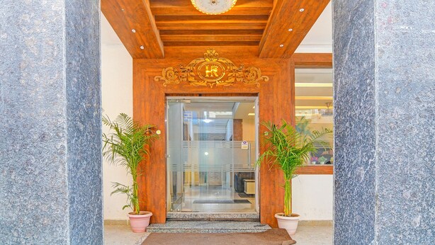 A hotel entrance with a wooden ceiling, a glass door, and two potted plants. - Fabhotel Rajdhani Residency (Ranchi)