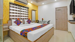 A bedroom with a bed, bedside tables, a desk, a chair, a television, and an air conditioning unit. - Fabhotel Rajdhani Residency (Ranchi)