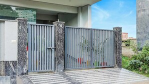 A gated entrance with a metal gate and a marble-like textured wall. - Fabhotel The Glampoint (Noida)