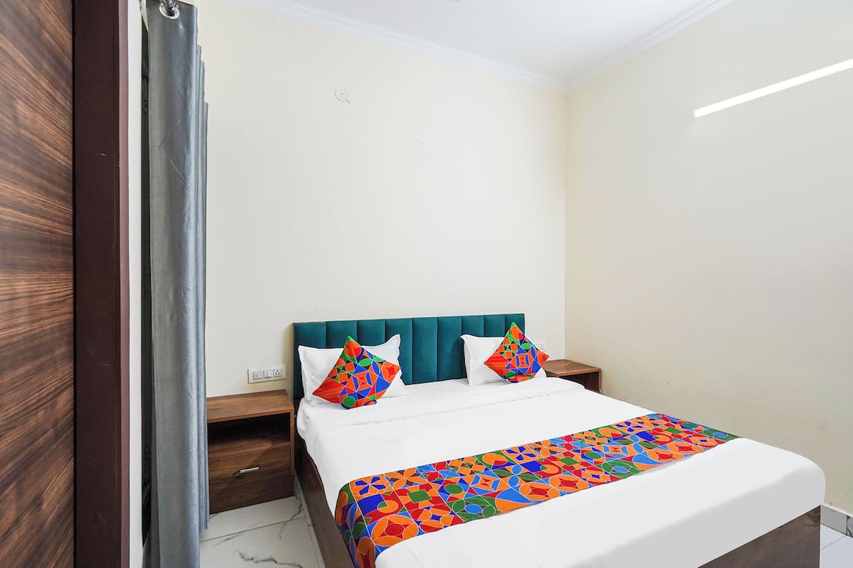 A hotel room with a bed, a nightstand, and a wooden wardrobe.