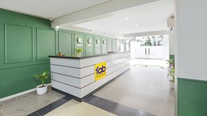 A reception area with a green wall, a reception desk, and a sign for 'fab hotels'. - Fabhotel The White Pepper (Faridabad)