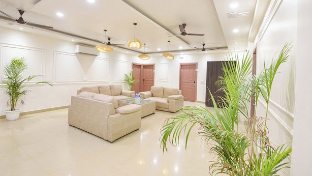 A spacious living area with a sofa set, ceiling fans, and hanging lights. - Fabhotel The White Pepper (Faridabad)