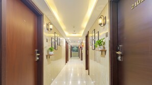A hotel corridor with wooden doors, framed artwork, and potted plants. - Fabhotel Western Inn (Chennai)
