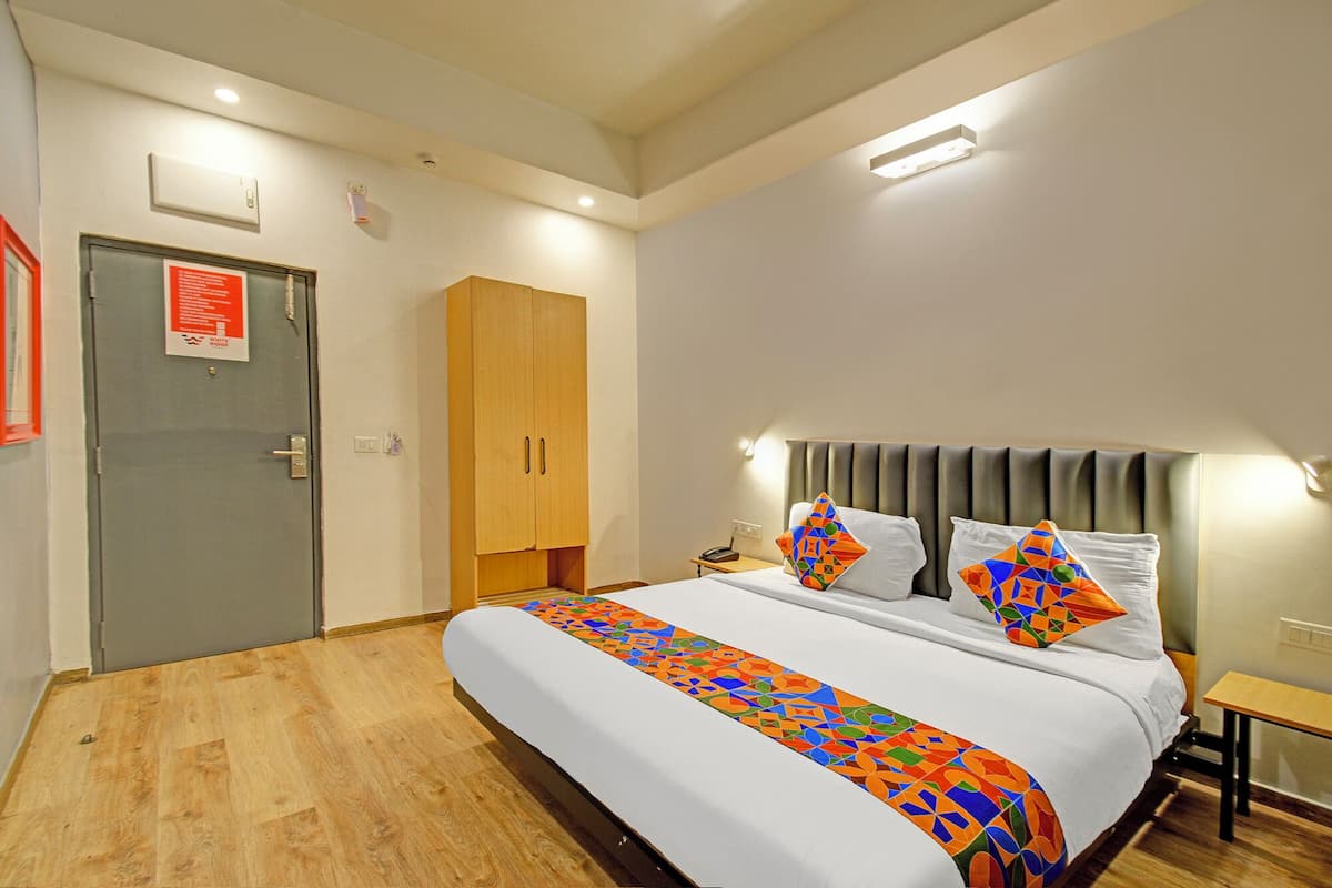 A hotel room with a bed, a wardrobe, a bedside table, and a nightstand.