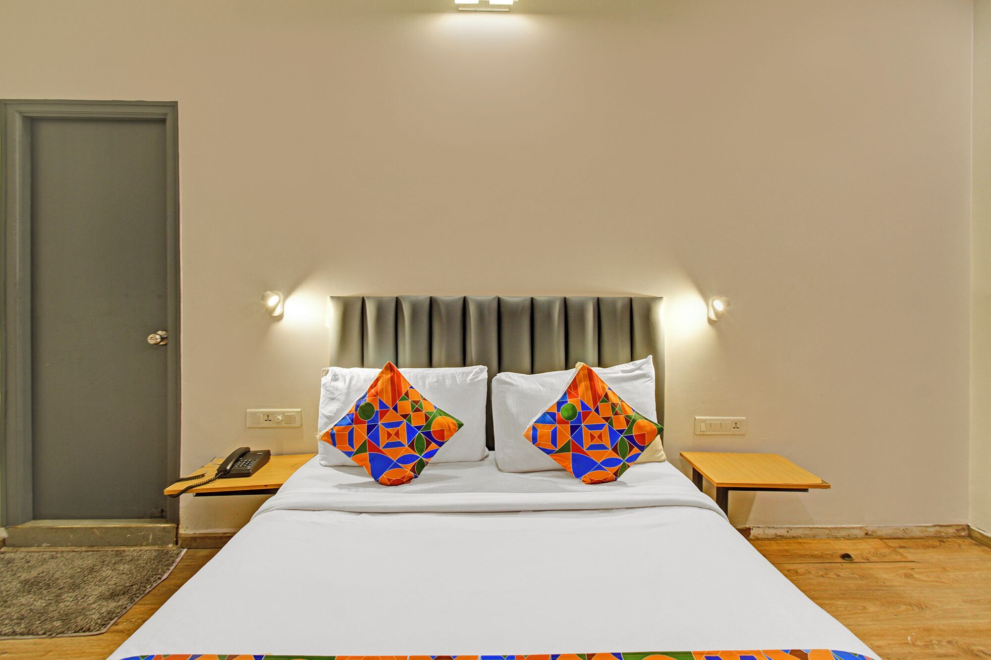 A hotel room with a bed, two nightstands, a telephone, and a door.